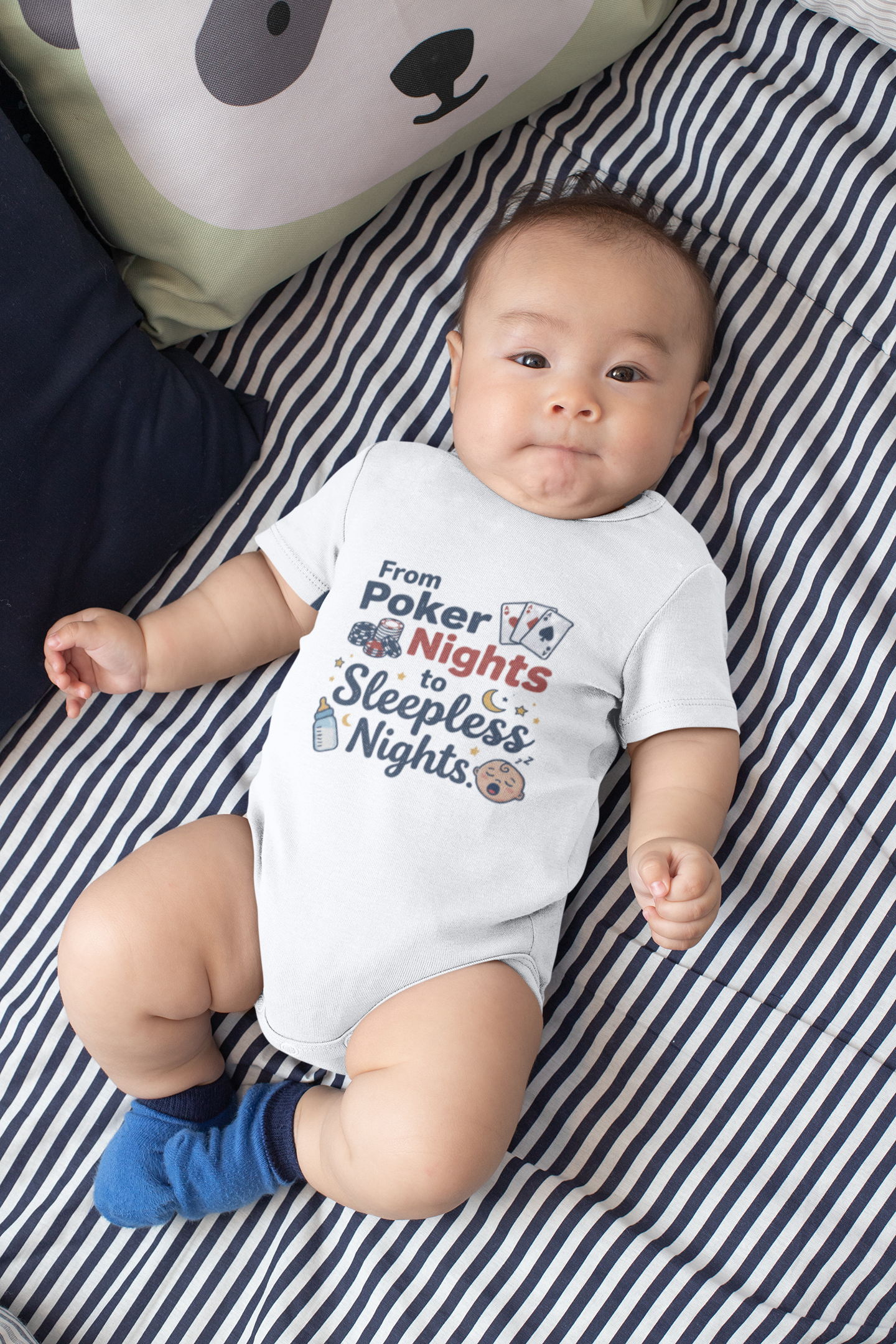 Baby wearing a onesie with text lying on a striped blanket